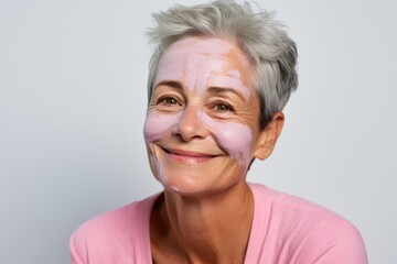 Against a backdrop of purity, a woman with cream on her face emphasizes the care and self-love involved in the aging skincare routine - obrazy, fototapety, plakaty