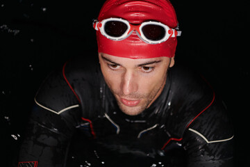Authentic triathlete swimmer having a break during hard training on night