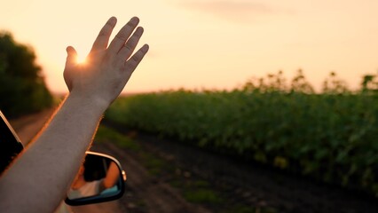 Man driver traveler raises his hand from window of car plays with his fingers with suns rays....