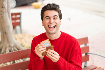 Young handsome man holding wallet with money with happy expression