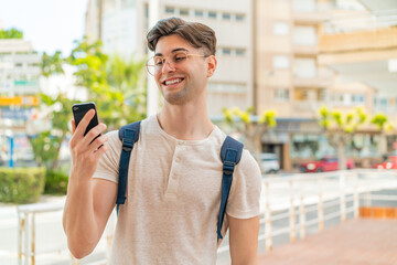 Young handsome man using mobile phone at outdoors with happy expression