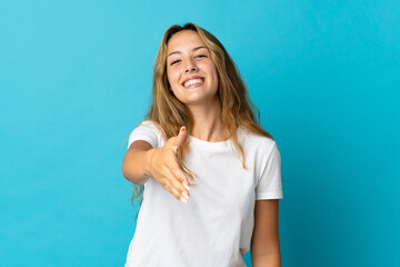 Young blonde woman isolated on blue background shaking hands for closing a good deal