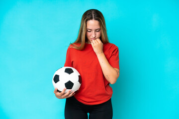 Young football player woman isolated on blue background having doubts