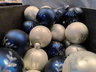 Decorated white and blue colored Christmas baubles in baskets on store shelves ready to be sold to visitors during a Christmas show during Christmas season