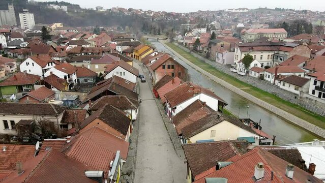 Drone flies above a street with cars driving on a road next to a a river in Valjevo