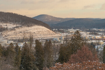 Bradford Pennsylvania, USA: November 29 2023 Oil refinery during winter snowy morning rising sunlight, historic cementary overlooking the town of bradford, oil refinery