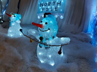 Transparent snowmen ornaments and a beautifully decorated signpost showing north pole are made of...