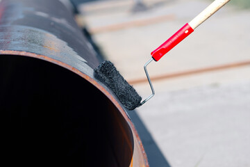 Metal pipe is painted with paint roller with black paint or bitumen. Protection of metal pipes from...