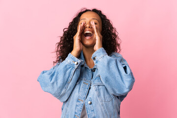 Teenager cuban girl isolated on pink background shouting and announcing something