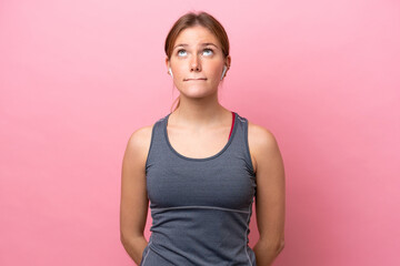 Young sport caucasian woman isolated on pink background and looking up