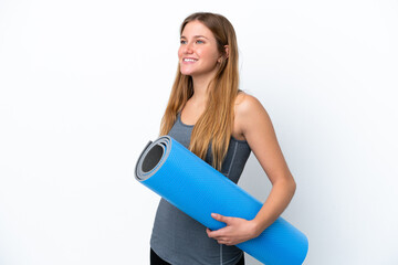 Young sport woman going to yoga classes while holding a mat looking side