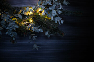 Section of pine and eucalyptus Christmas wreath, with illuminated string lights. Background with copy space. © silvia