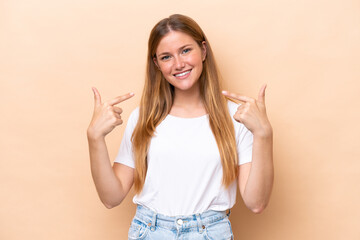 Young caucasian woman isolated on beige background giving a thumbs up gesture