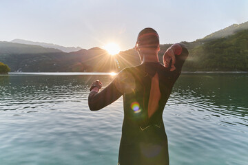 Authentic triathlon athlete getting ready for swimming training on lake