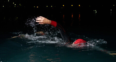 A determined professional triathlete undergoes rigorous night time training in cold waters, showcasing dedication and resilience in preparation for an upcoming triathlon swim competition
