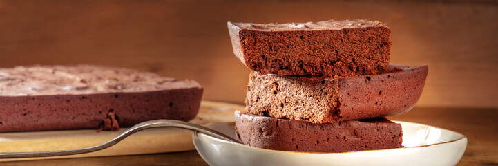 Chocolate brownie panorama, simple coffee cake, a side view shot on a dark rustic wooden background