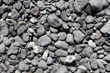 Volcanic rocks texture. Rocky beach on Canary Islands. Tenerife black beach. Small stones background. Atlantic ocean beach. Black and dark gray black rocks.