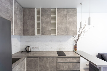 Spacious kitchen with minimalist square shaped furniture, grey floor and walls, counter with...