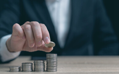 Businessman places coins on piles in tiers. Financial concepts, saving, saving, investing, depositing money, saving for stability in life. and marketing business