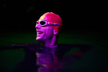 Authentic triathlete swimmer having a break during hard training on night neon gel light