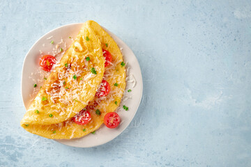 An omelet with tomato and parsley, eggs for breakfast, a healthy vegetarian dish with cheese, overhead flat lay shot with copy space - obrazy, fototapety, plakaty
