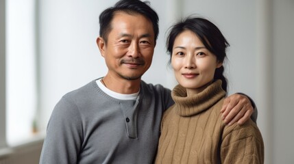 Obraz premium Finding peace in each other's arms, an Asian middle-aged couple shares a heartfelt embrace at home.