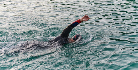 A professional triathlete trains with unwavering dedication for an upcoming competition at a lake,...