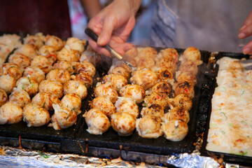 Vendor making takoyaki on a takoyaki pan in Kyoto, Japan. Takoyaki is famous street food in Kyoto.