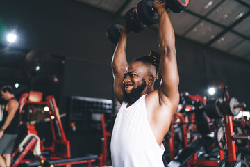 Fototapeta na wymiar Strong black man lifting dumbbells in gym