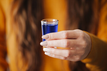 Girl holding vodka shot. Woman drinking vodka background. Homemade blueberry vodka. Funny blue...
