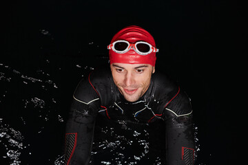 Authentic triathlete swimmer having a break during hard training on night