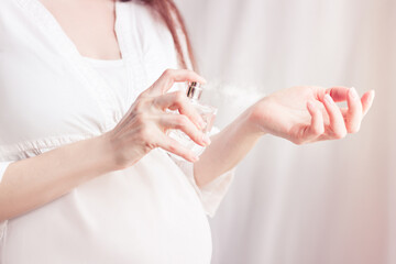 pregnant girl sprays perfume on her wrist