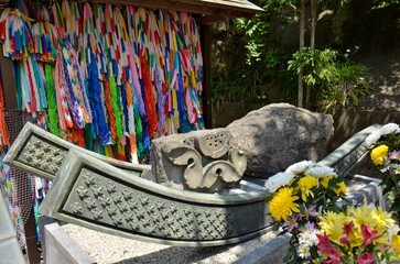 大船観音寺境内に建立されている原爆犠牲者慰霊碑横の被爆石です。爆心地の西蓮寺からは地蔵尊の土台石、長崎の浦上天主堂からも石が寄贈されました。それぞれの被爆石は千羽鶴が刻まれた筏にのせられ、その台座には被爆者が平和の丘に向かう姿が描かれています。また、その慰霊碑の右手には原爆の火の塔があります。ぜひみなさまも恒久平和祈願にお参りくださいませ。