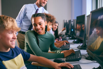 Multi-Cultural Group Of Secondary Or High School Students At Computers In IT Class With Male Teacher
