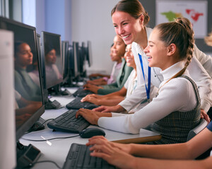 Group Of Secondary Or High School Students At Computers In IT Class With Female Teacher