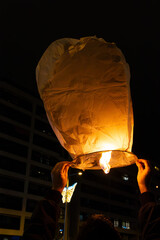 person with his back turned, holding a Chinese lantern of light, burning with his hands. christmas