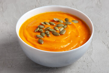 Pumpkin soup with seeds on a gray background, taken close-up from above. Concept of healthy vegetable soups