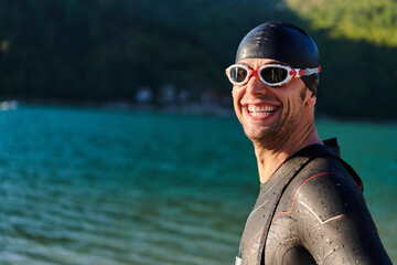 Authentic triathlon athlete getting ready for swimming training on lake