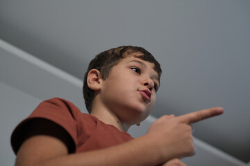 Young boy pointing upwards with a curious expression, shot from a low angle. Captures the essence...