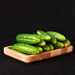 cucumbers on a wooden board close-up, dark background, no people
