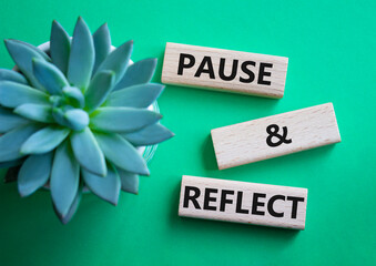 Pause and Reflect symbol. Concept words Pause and Reflect on wooden blocks. Beautiful green...