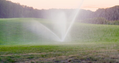 medium shot of grass sprinkler splashes water over the lawn