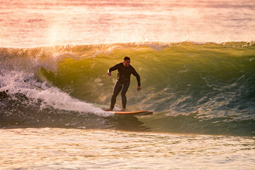 Young Man Riding Wave at Sunset