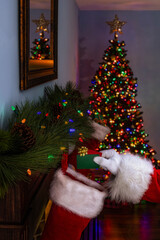 Fototapeta na wymiar Santa Claus placing 2 gift cards into a stocking hanging on mantlepiece