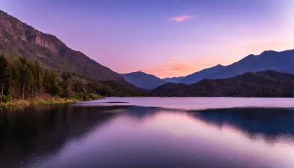 Fototapeten lake surrounded by forested mountains under a purple sky at sunset © Paula