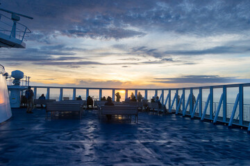 Obraz premium Silhouette of Tourists Enjoying Beautiful Orange Sunset seen from a ferry between Denmark and Iceland in the Atlantic Ocean