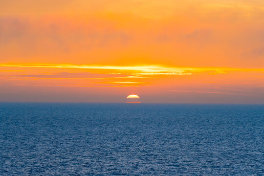 Beautiful Sunset in the Atlantic Ocean with orange sky and blue ocean somewhere in Faroe Islands