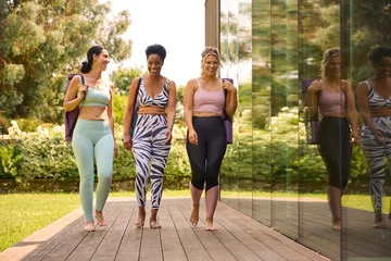Crédence de cuisine en verre imprimé Fitness Three Mature Female Friends Outdoors In Fitness Clothing Carrying Exercise Mats At Gym Or Yoga Class