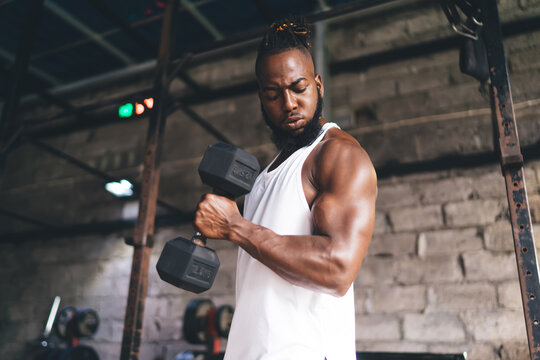 Strong black male athlete exercising with dumbbell