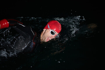 A determined professional triathlete undergoes rigorous night time training in cold waters,...